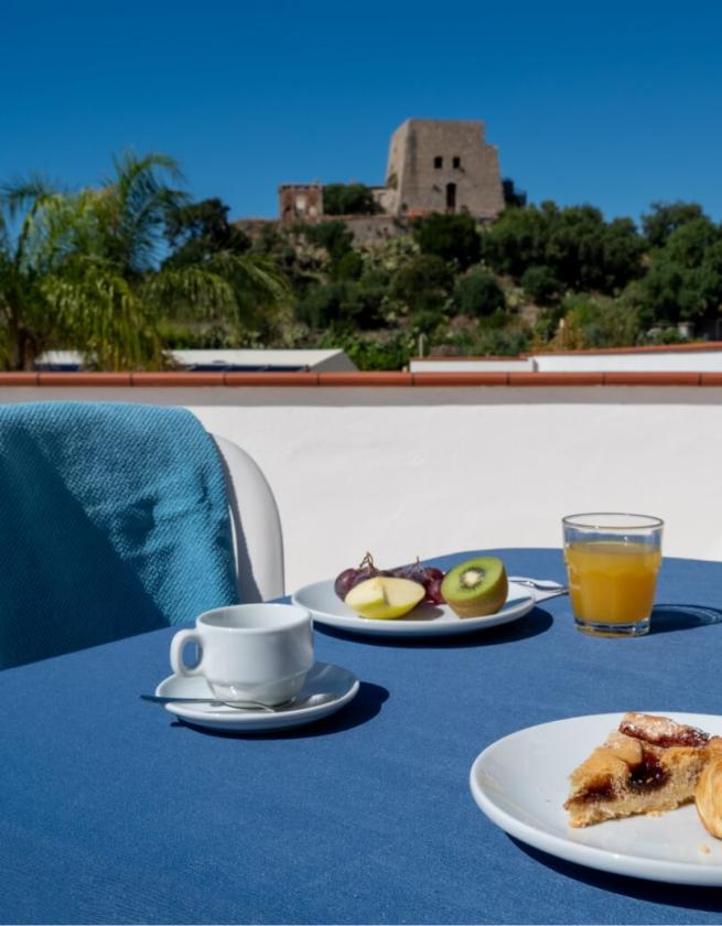 Colazione all'aperto con vista su un castello, frutta e succo d'arancia.